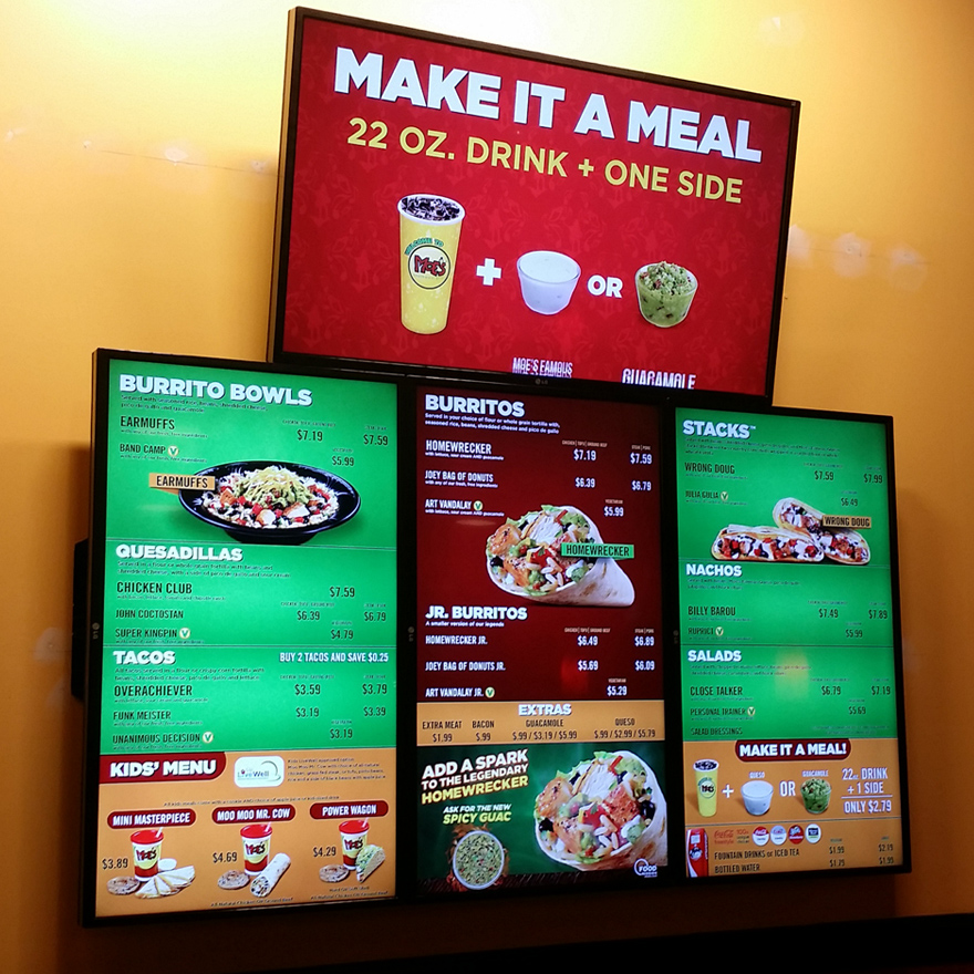 Three vertical digital menu boards display food options like tacos, burritos, and beverages and a horizontal board shows a special offer above.