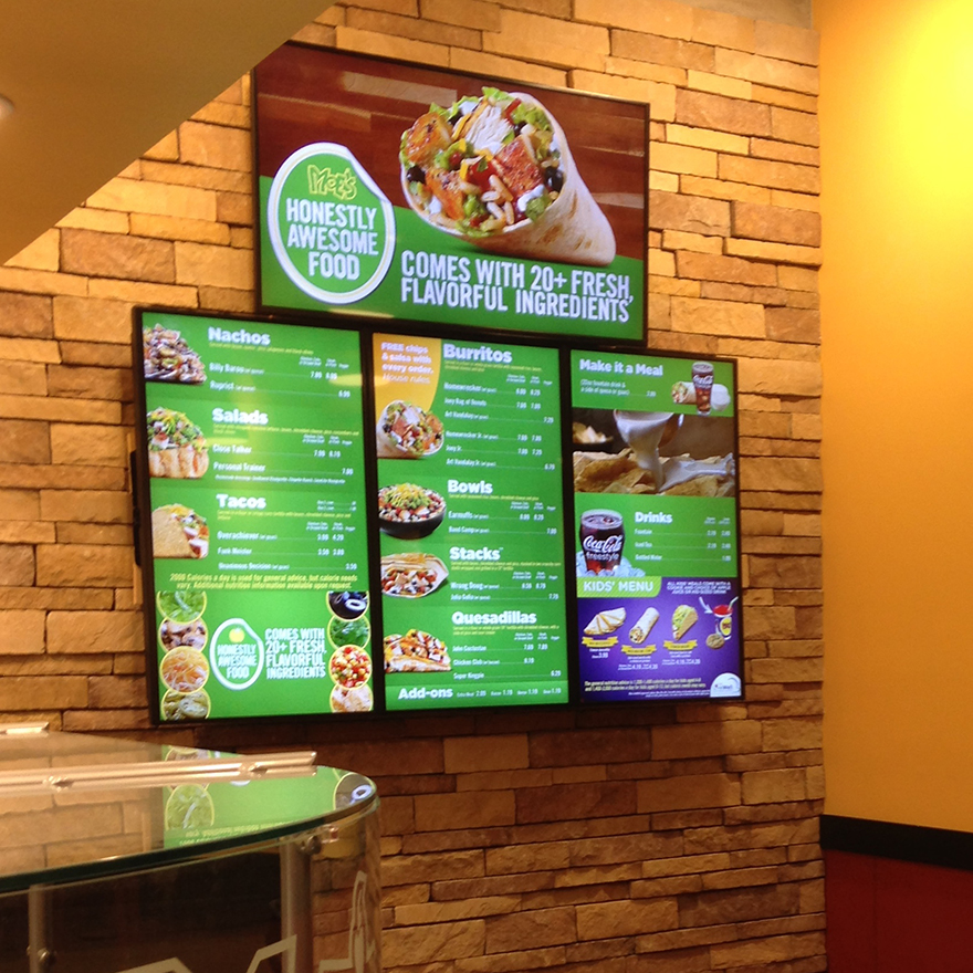 Three vertical digital menu boards display food options like tacos, burritos, and beverages.