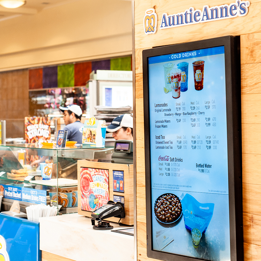 An Auntie Anne's digital menu is in the foreground of the restaurant's storefront.