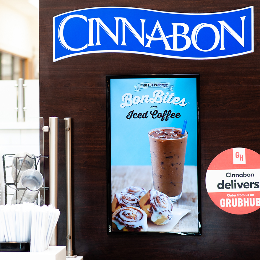One vertical video board advertises BonBites and Iced Coffee at a Cinnabon.