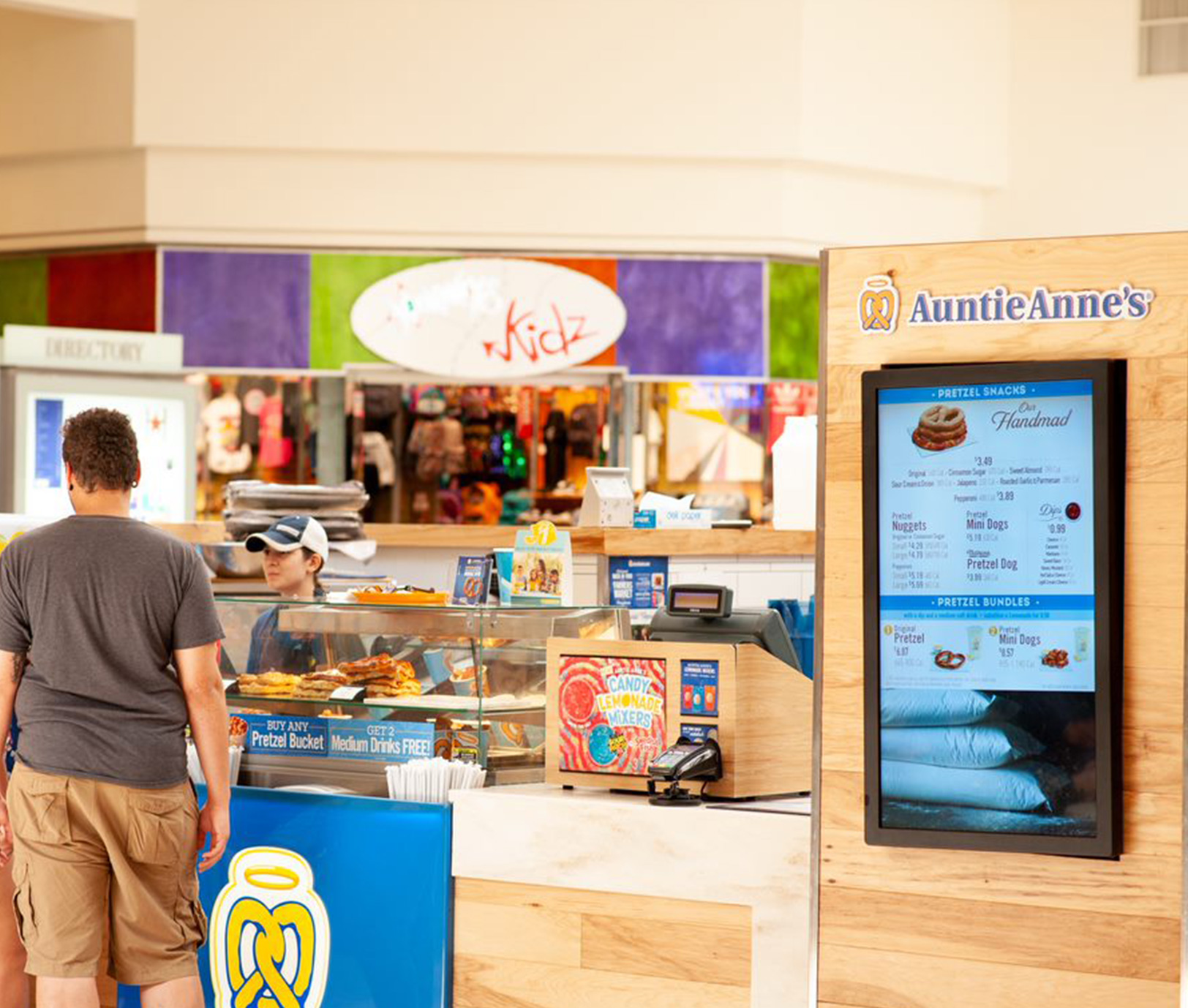 An Auntie Anne's menu board is mounted vertically with the cash register and counter in the background.							